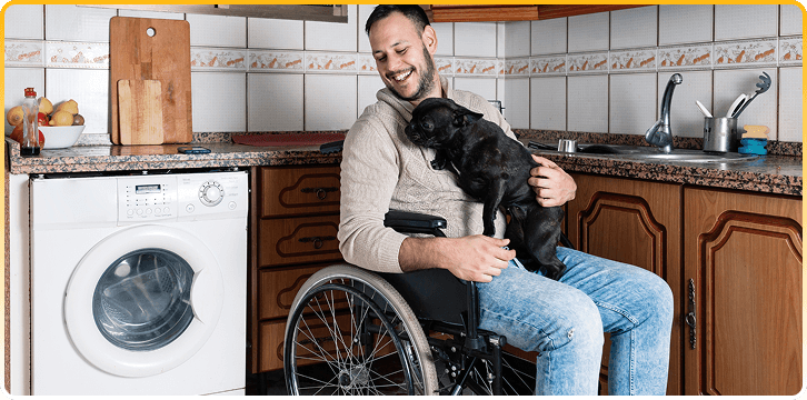 Man In Wheelchair With Dog In Kitchen